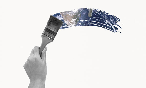 Hand holding paintbrush painting the world