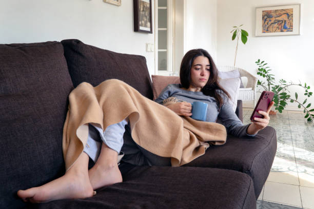 istock Young woman lying on the sofa using mobile phone 2198403461