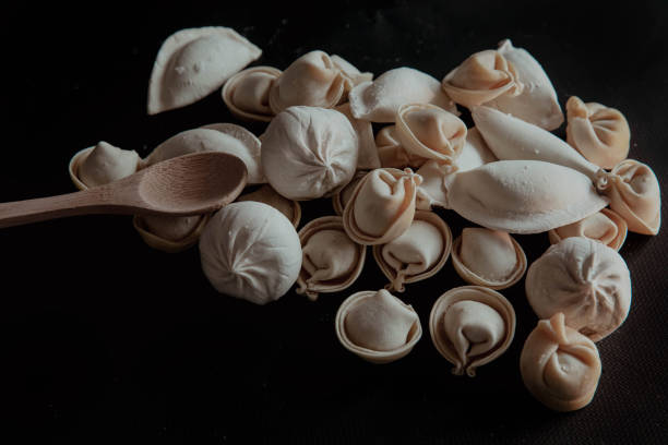 istock Dumplings on black background with wooden spoon 2198403568