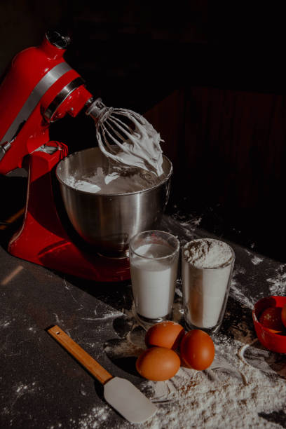 istock Ingredients for pie. Flour, eggs, milk, mixer with cream on dark background 2198404569