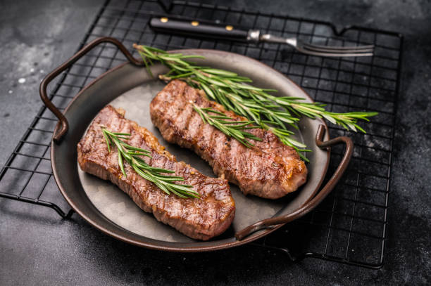 istock BBQ roast marbled beef Steak, beef meat on tray with herbs. black background. top view 2198404711