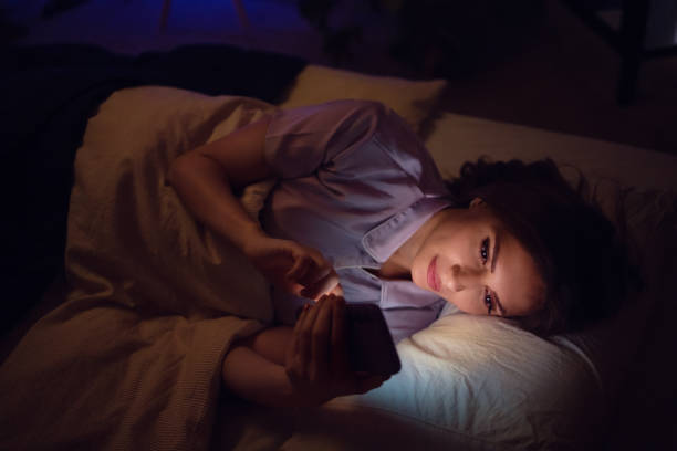 istock Woman Relaxing in Bed at Night Using Her Smartphone in Dim Light 2198405223