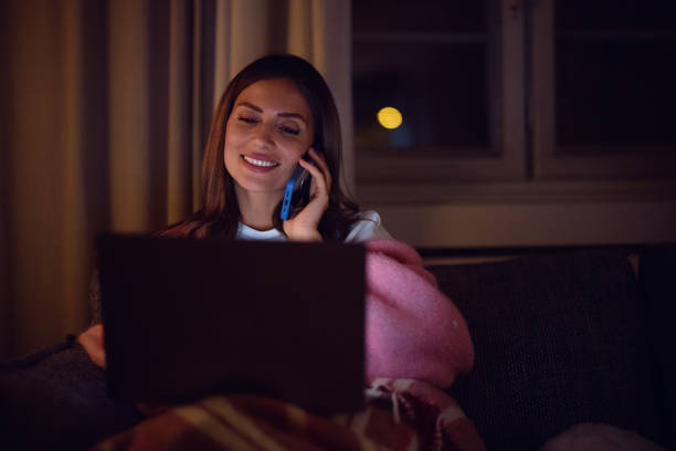 istock Young Woman Smiling While Talking on Phone and Using Laptop Indoors 2198405246