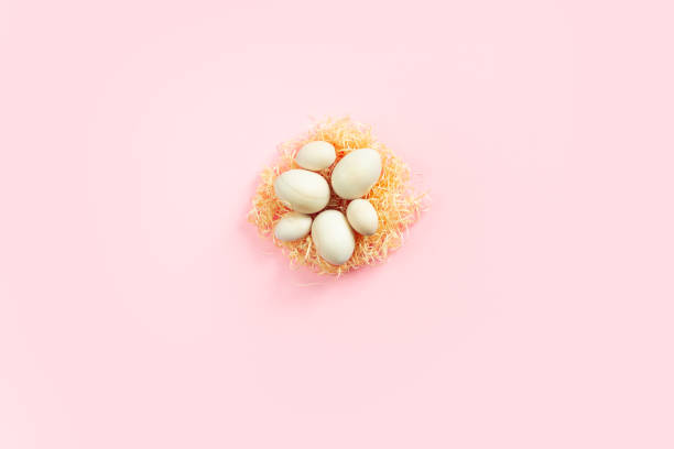 istock Wooden eggs lying on artificial nest in the center on pink background. Easter eco-friendly concept 2198405547