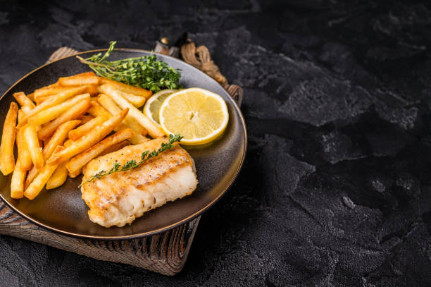 istock Homemade Fish and chips with roast cod whitefish fillet and fried potatoes on plate. black background. top view 2198405769