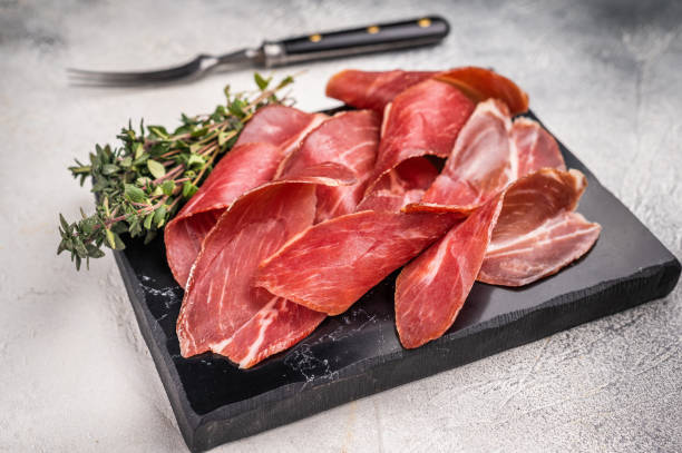 istock Sliced Speck bacon, Italian cured meat. grey background. top view 2198407172