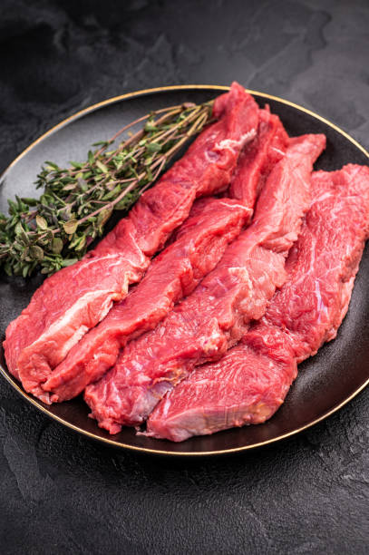 istock Raw sliced horse meat steaks presented with herbs and spices, inviting creativity in the kitchen for those seeking bold flavors and unique dining experiences. black background. top view 2198407252