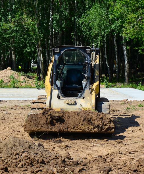 istock Mini excavator digging and pushing ground in construction site near park. 2198407283