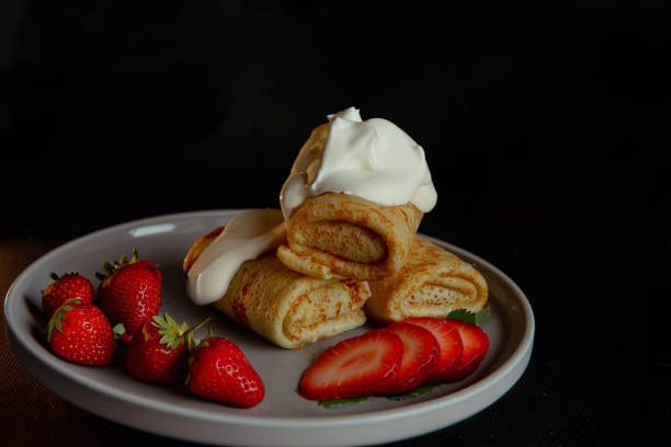 istock Spring rolls pancakes on a plate with berries on a black background 2198408799