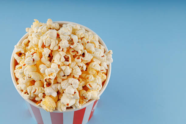 istock Classic red striped popcorn cardboard cup on blue background 2198411971