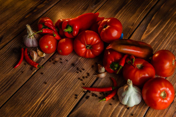 Red tomatoes and peppers on wooden table.