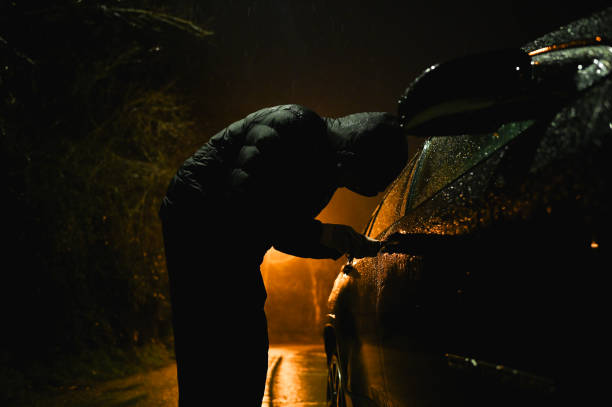 Man with hood trying to break into car.