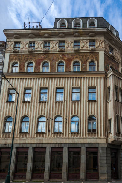 istock A multi-story building with a decorated facade featuring rows of arched windows, contrasting textures, and a dark-colored upper level under a cloudy sky 2198424149