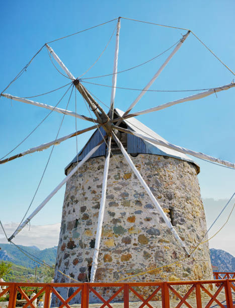 A traditional stone windmill with a wooden fence and vivid blue skies, situated among scenic Turkish hills. This image embodies history, heritage, and the timeless beauty of Turkey's countryside.