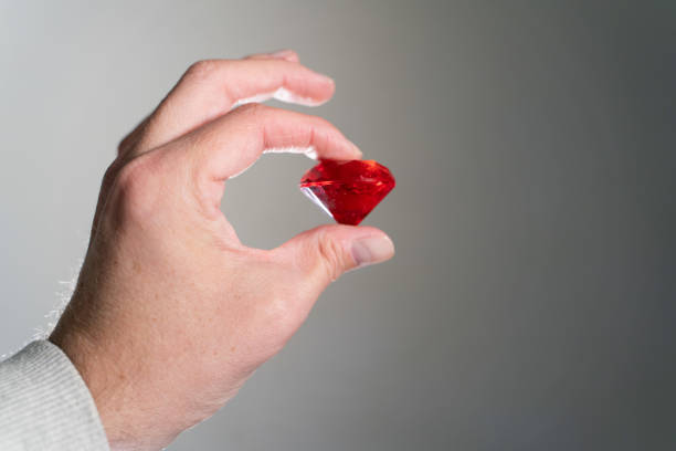 Hand Holding Red Ruby Diamond, Precious Gem Crystal on Grey Background, Luxury Jewelry Concept, Luxury Red Gemstone Crystal