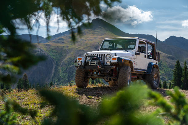 Off-Road Vehicle Parked on Scenic Mountain Trail Surrounded by Nature An off-road vehicle rests on a mountain trail, showcasing rugged terrain and natural beauty. The setting exemplifies outdoor adventure and exploration, with greenery and imposing mountains forming the backdrop. 4x4 stock pictures, royalty-free photos & images