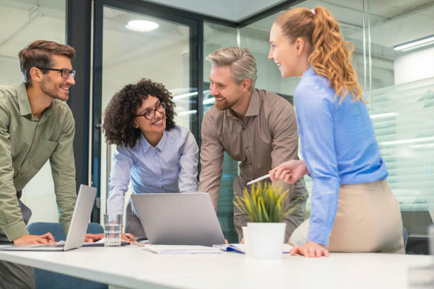 istock Happy four business people executive team working at laptop having discussion at office meeting showing financial project 2198463055
