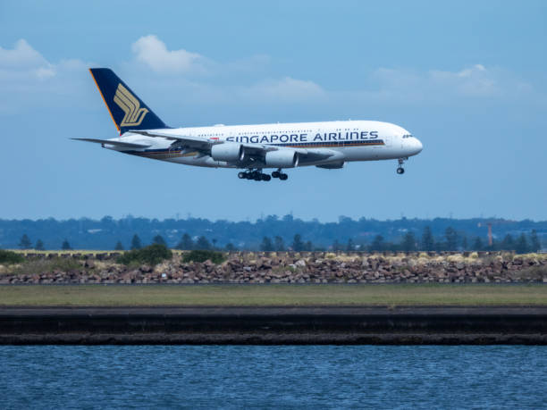 A Singapore Airlines Airbus A380-841 plane, registration 9V-SKU, landing at Sydney Kingsford Smith Airport as flight SQ231 from Singapore. In the foreground is Botany Bay and the seawall of the third runway. This image was taken from near the Port Botany Boat Ramp, Botany Bay, on a hot and sunny morning on 8 February 2025.