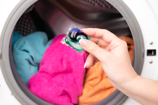 istock A woman's hand throws a laundry capsule into the washing machine 2198474783