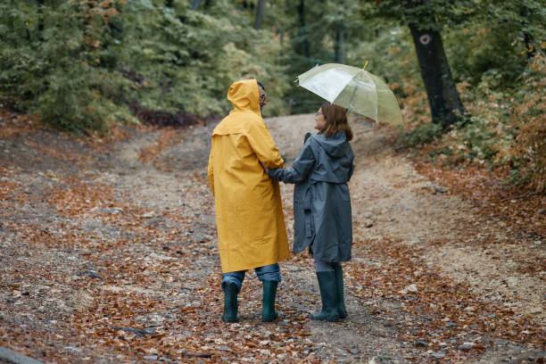 istock Happy embraced senior couple walking with umbrella at forest 2198475267
