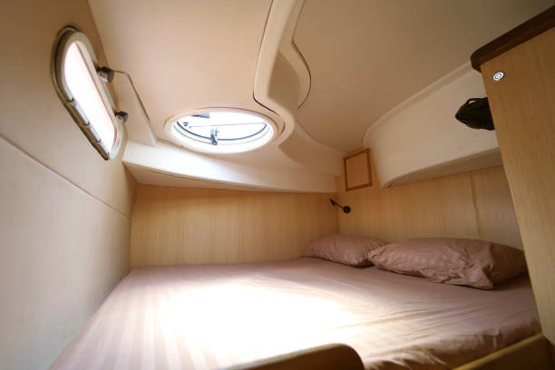 Cozy bed on a voyage boat with a window overhead with natural light.