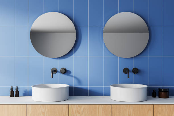 istock Modern bathroom with round mirrors and white sinks on wooden vanity against blue tiled wall. 3D Rendering 2198487818