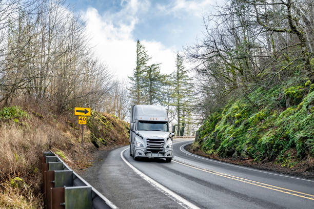istock White high cab big rig semi truck transporting cargo in refrigerator semi trailer driving on the winding road in Columbia Gorge 2198489855