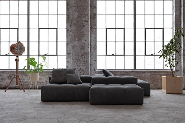 istock Industrial loft with large windows, dark sofa, and plants. 2198490079