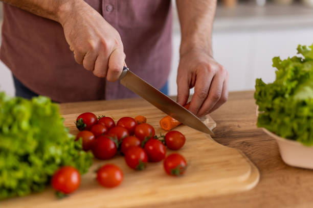 istock Handsome young man man stand at modern kitchen chop vegetables prepare fresh vegetable salad for dinner or lunch, young male cooking at home make breakfast follow healthy diet, vegetarian concept 2198490471