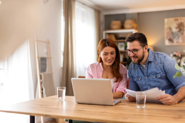 istock A smiling couple collaborates on financial planning at home, using a laptop and discussing important documents. Their teamwork and organization reflect a positive and balanced lifestyle. 2198490645