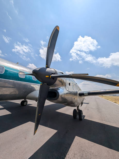 Propeller airplane is parked on the runway of Arusha Airport, ready for take-off or after landing, under a beautiful blue sky with some clouds