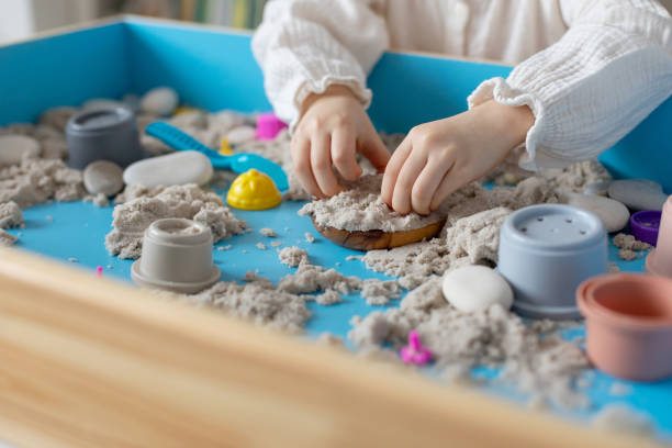 istock Children activity with kinetic sand for motor and sensory development. Toddler play therapy with colorful toys on sandbox. 2198498079