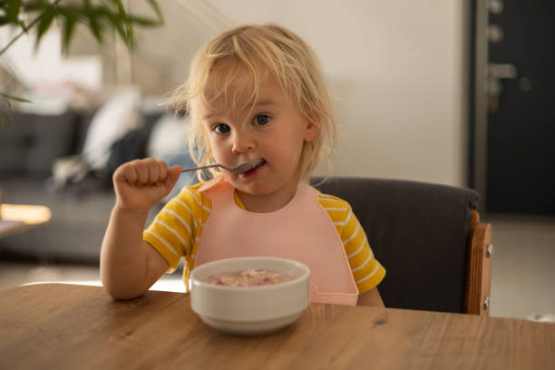 istock Child enjoying breakfast with yogurt in a modern kitchen setting in the morning 2198498136