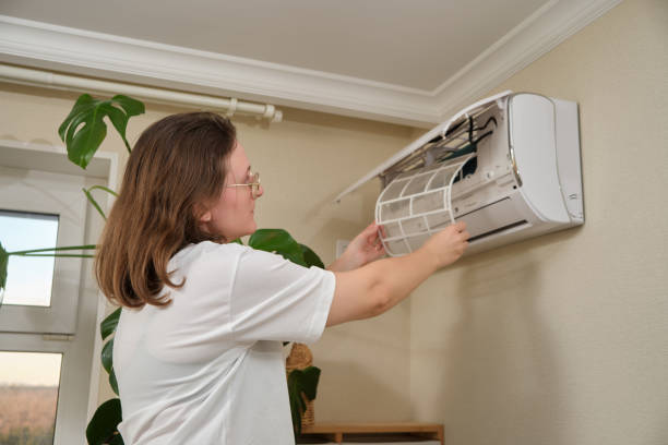 istock Cleaning air conditioner filter. Woman removing dust filter from wall-mounted split air conditioning unit for maintenance. Home appliance care and HVAC system maintenance. 2198502175