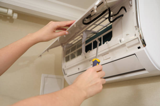 istock Woman's hand holding screwdriver while repairing wall-mounted air conditioner. HVAC maintenance and repair concept. 2198502197
