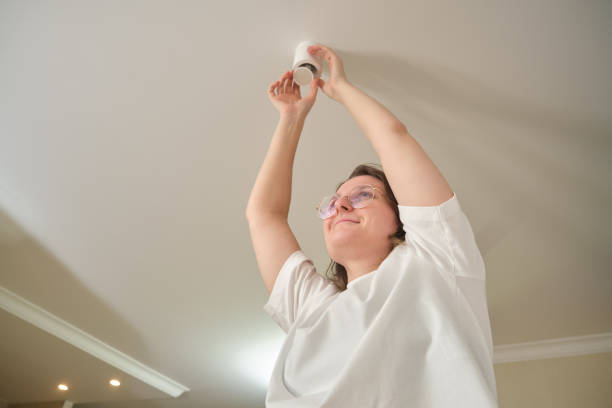 istock Woman replacing a ceiling light fixture. Home lighting and interior maintenance concept 2198502201