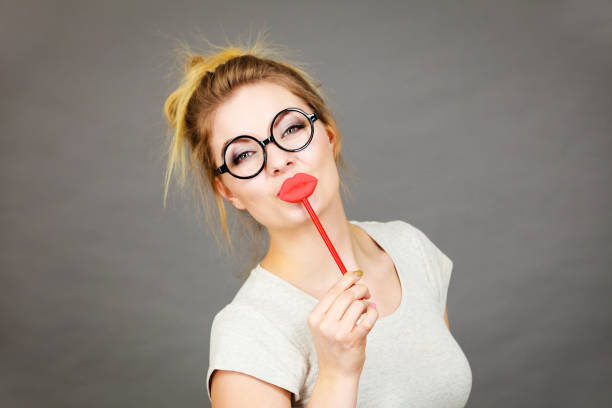 Young woman with love sunglasses, colorful clothes, purple background being surprised or embarressed.