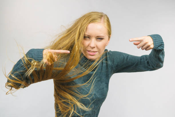portrait of beautiful young white woman with blonde hair posing at gray background