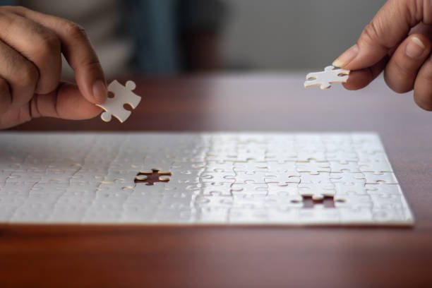 istock Two people working together to put together a jigsaw puzzle. 2198505576