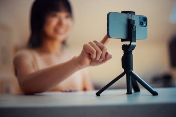 istock Woman Recording Video on Smartphone With Tripod in a Home Setting 2198506451