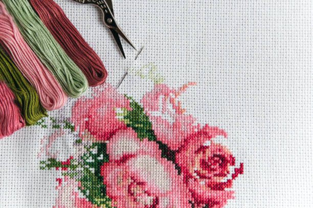 istock cross stitch process pink flowers on a white canvas aida 14 counts, pink thread floss, needle, vintage scissors for needlework 1 2198512000