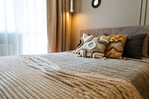 istock A cozy bed with a soft blanket and fluffy pillows sits near a sunny window, streaming natural light that enhances the rooms warmth and creates an inviting atmosphere of comfort 2198512350
