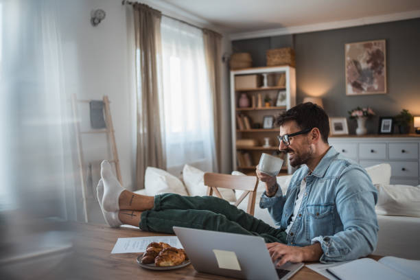 istock Young man sipping coffee while working in his home office 2198514539