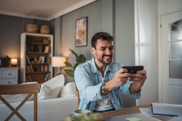 istock Young adult man gaming on his mobile phone after a productive workday 2198514802