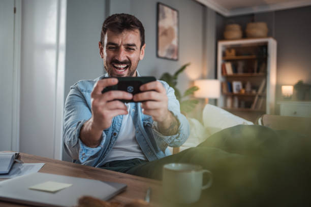istock Man unwinding with mobile games after a busy workday 2198514943