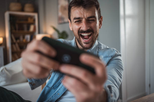 istock Man having fun playing games on his phone 2198515051
