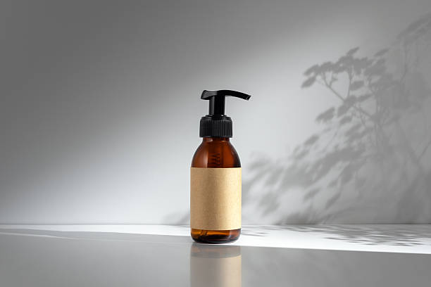 istock Amber glass pump bottle with blank label on a neutral background with soft plant shadows 2198516245