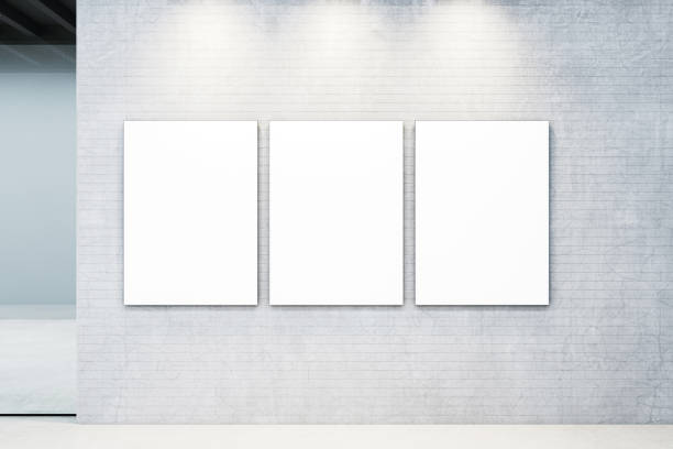 istock Three blank vertical canvases on a textured concrete wall in a modern gallery under spotlights. 3D Rendering 2198517157
