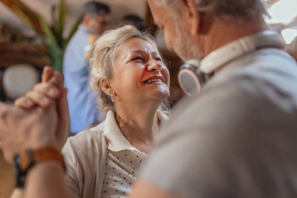 istock Happy senior people having music party in their home. They holding a microphone and singing karaoke. Senior people leisure time concept. 2198517543