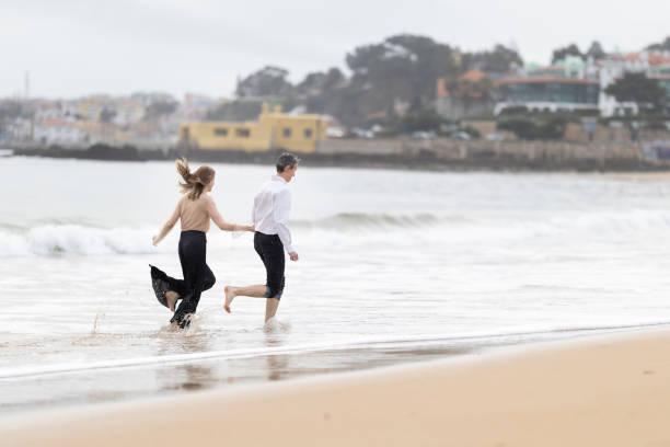 istock Couple running on the beach holding hands on a cloudy day 2198519030